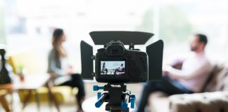 Reporter interviewing businessman seen on video camera display at office