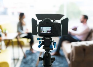 Business leaders: The message is your business Reporter interviewing businessman seen on video camera display at office