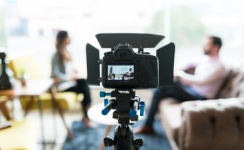 Reporter interviewing businessman seen on video camera display at office