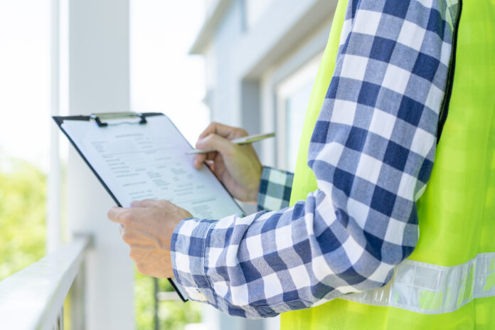 inspector or engineer is inspecting construction and quality assurance new house using a checklist. Engineers or architects or contactor work to build the house before handing it over to the homeowner