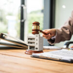 A young businesswoman is working at her desk, managing lease agreements and coordinating with the HOA for an apartment complex, focusing on tenant relations and property maintenance.